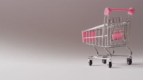 Leerer-Rosafarbener-Einkaufswagen-Auf-Nahtlosem-Grauen-Hintergrund