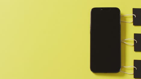 Draufsicht-Auf-Das-Smartphone-Und-Drei-Schwarze-Verkaufsetiketten-Auf-Gelbem-Hintergrund-Mit-Platz-Zum-Kopieren