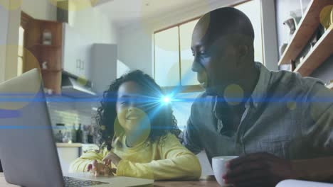 Animation-of-light-spots-and-trails-over-african-american-man-and-his-daughter-using-laptop-together