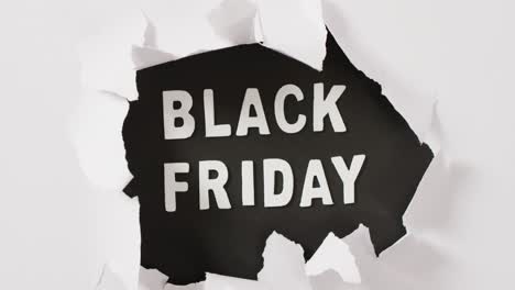 Ripped-white-paper-over-black-friday-text-in-white-on-black-background
