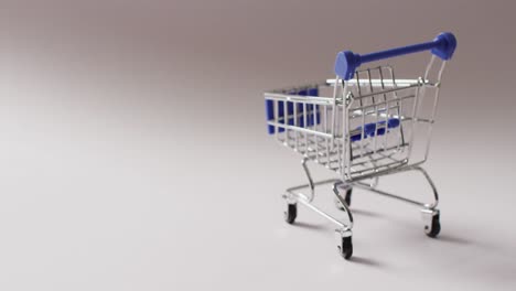Empty-blue-shopping-trolley-on-seamless-grey-background