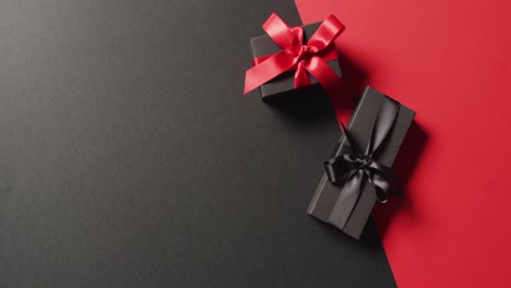 Draufsicht-Auf-Zwei-Schwarze-Geschenkboxen-Mit-Roten-Und-Schwarzen-Bändern-Auf-Schwarz-Und-Rot-Mit-Kopierraum