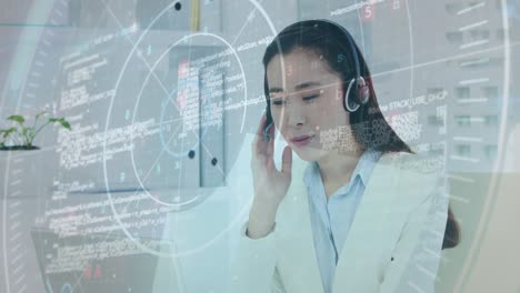Animation-of-data-processing-over-asian-businesswoman-wearing-phone-headset-using-laptop-at-office