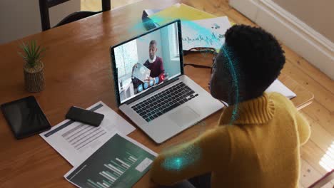 Animation-of-spinning-globe-over-african-american-woman-having-a-video-call-on-laptop-at-home