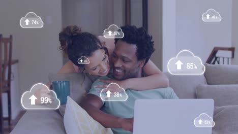 Animation-of-cloud-icons-over-african-american-couple-using-laptop