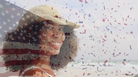 Animation-of-flag-of-united-states-of-america-over-happy-african-american-woman-on-beach