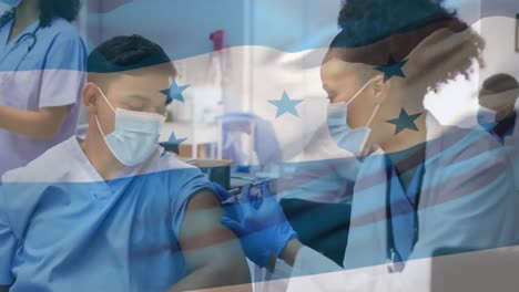Animation-of-flag-of-honduras-over-african-american-female-doctor-with-vaccine