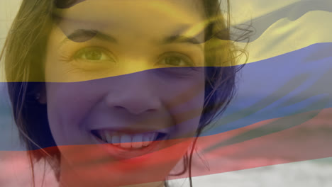 Vídeo-Compuesto-De-Ondear-La-Bandera-De-Columbia-Sobre-El-Retrato-De-Una-Mujer-Caucásica-Sonriendo-En-La-Playa