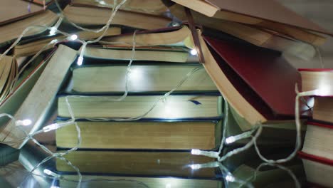 Video-of-christmas-fairy-lights-and-stack-of-books-on-wooden-background