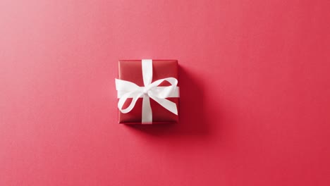 Video-of-red-christmas-gift-and-copy-space-on-red-background