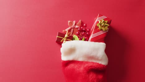 Video-of-christmas-gifts-in-christmas-stocking-and-copy-space-on-red-background
