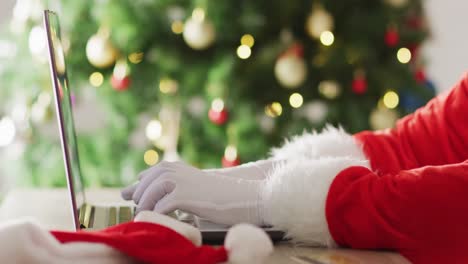 Papá-Noel-Usando-Una-Computadora-Portátil-Sobre-El-árbol-De-Navidad-Y-Las-Luces