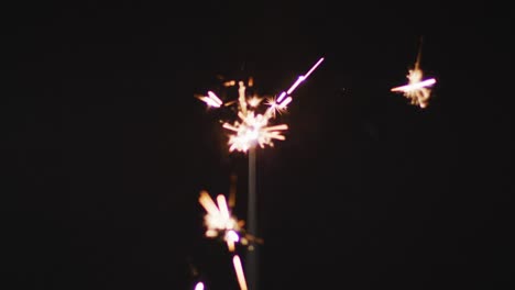 Video-of-lit-sparkler-burning-on-black-background,-with-copy-space