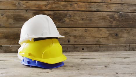 Video-of-close-up-of-colourful-building-helmets-on-wooden-background