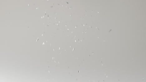 Video-of-glittering-silver-confetti-falling-on-white-background