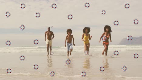 Animation-Von-Rettungsringen-über-Glücklichen-Afroamerikanischen-Eltern-Und-Kindern,-Die-Vom-Meer-Zum-Strand-Rennen