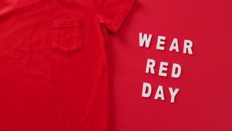 Video-of-close-up-of-wear-red-day-text-and-red-tshirt-on-red-background