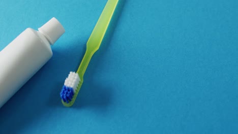 Video-of-close-up-of-toothbrush-and-paste-on-blue-background