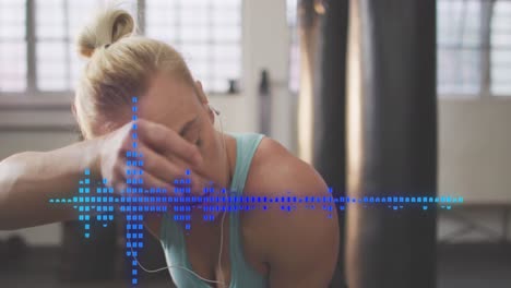Animation-of-audio-meter-over-caucasian-woman-in-gym-wearing-earphones
