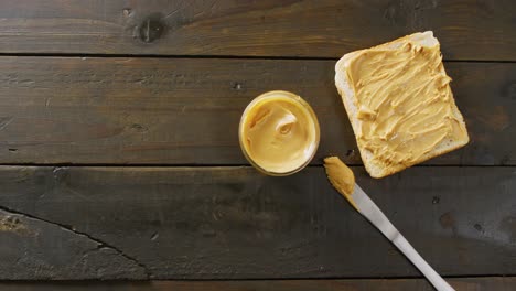 Video-of-close-up-of-toast-with-peanut-butter-on-wooden-background
