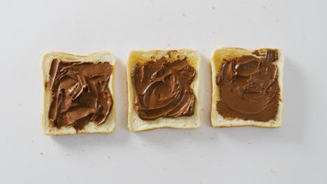 Video-of-close-up-of-toasts-with-chocolate-cream-on-white-background