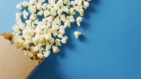 Video-of-close-up-of-box-of-popcorn-on-blue-background