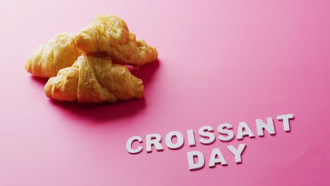 Video-of-close-up-of-croissants-and-croissant-day-text-on-pink-background