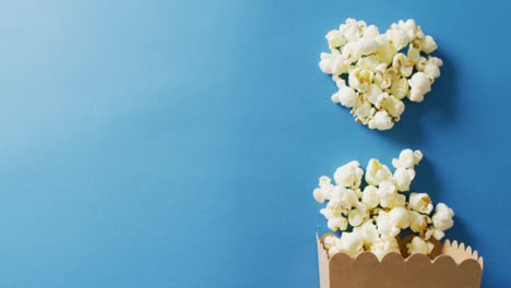 Video-of-close-up-of-box-of-popcorn-on-blue-background