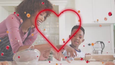 Animation-of-red-heart-and-fruits-over-happy-african-american-mother-and-son-baking-in-kitchen