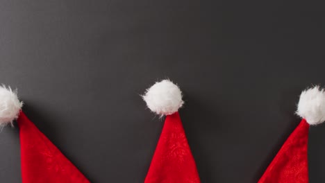 Video-of-close-up-of-santa-hats-on-gray-background
