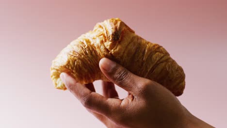 Video-of-close-up-of-hand-with-croissant-on-white-background