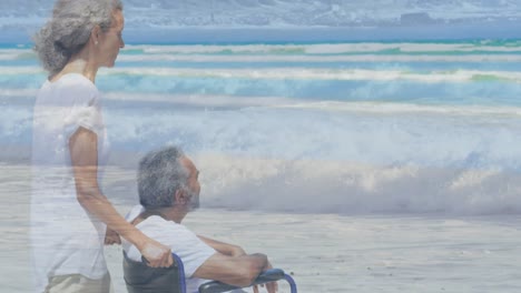 Animation-of-sea-over-biracial-woman-with-man-in-wheelchair