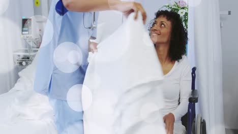 Animation-of-spots-over-african-american-female-nurse-with-patient