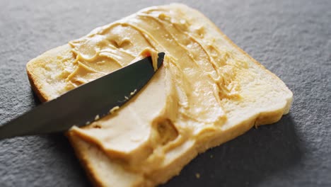 Video-of-close-up-of-toast-with-peanut-butter-on-gray-background