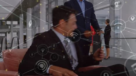 Animation-of-network-of-digital-icons-over-two-diverse-businessmen-shaking-hands-at-office