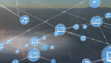 Animation-of-network-of-digital-icons-against-aerial-view-of-landscape-with-mountains