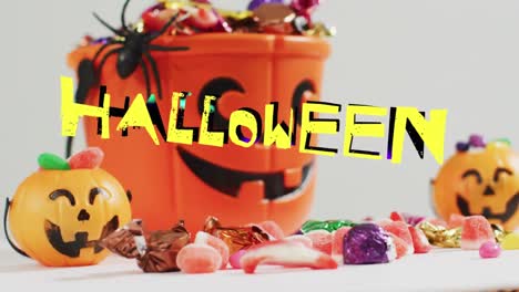 Animation-Von-Halloween-Text-über-Geschnitzten-Kürbiseimern-Mit-Süßigkeiten-Auf-Grauem-Hintergrund