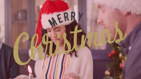 Animation-of-merry-christmas-text-over-diverse-friends-sitting-at-table-at-christmas