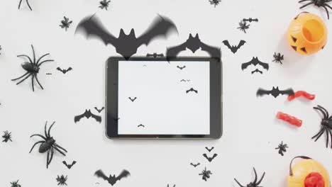 Animation-Von-Halloween-Spinnen,-Fledermäusen-Und-Dekorationen-über-Tablet-Auf-Weißem-Hintergrund