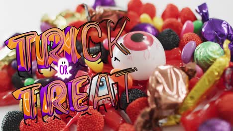 Animation-of-halloween-trick-or-treat-text-over-sweets-on-grey-background