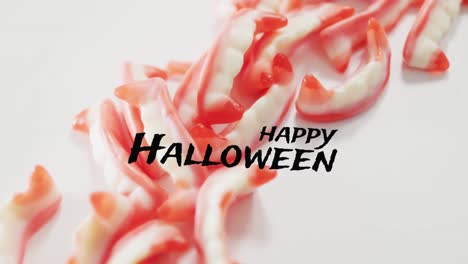 Animation-of-halloween-text-over-teeth-sweets-on-grey-background