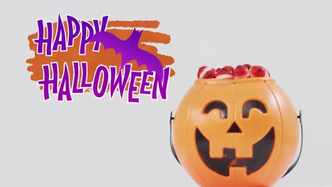 Animation-of-halloween-text-over-carved-pumpkin-bucket-with-sweets-on-grey-background