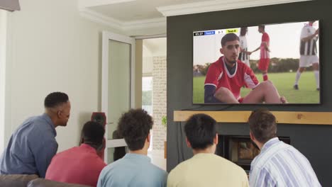 Video-Von-Verschiedenen-Freunden,-Die-Auf-Dem-Sofa-Sitzen-Und-Zu-Hause-Fußball-Im-Fernsehen-Schauen