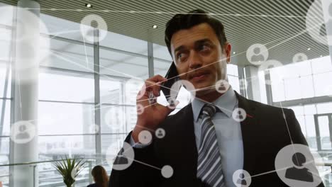 Animation-of-network-of-profile-icons-over-caucasian-businessman-talking-on-smartphone-at-office