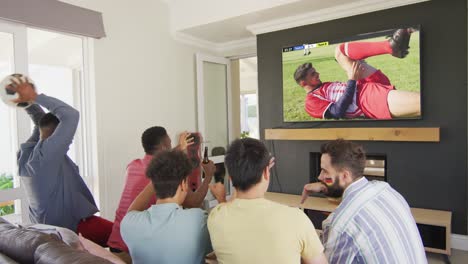 Diverse-friends-supporting-and-watching-tv-with-diverse-male-soccer-players-playing-match-on-screen