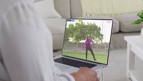 Hands-using-laptop-with-african-american-male-soccer-player-playing-match-on-screen
