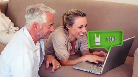 Animation-of-social-media-icon-with-growing-number-over-caucasian-couple-using-laptop