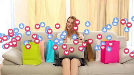 Animation-of-like-and-heart-icons-over-caucasian-woman-with-shopping-bags-and-laptop-celebrating