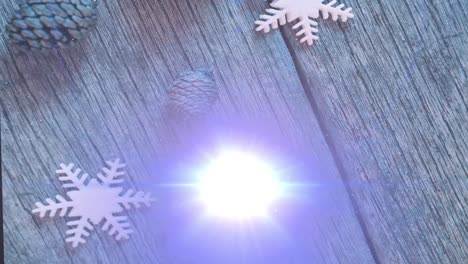 Animation-of-light-trails-and-snow-falling-over-christmas-decorations-on-wooden-background