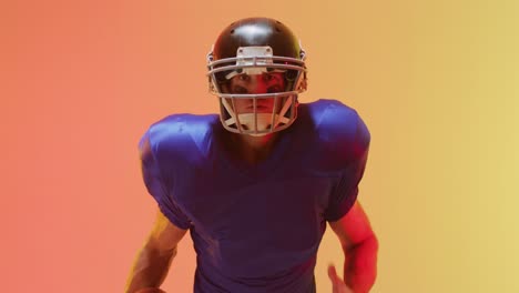 Video-Einer-Nahaufnahme-Eines-Kaukasischen-American-Football-Spielers-Mit-Helm-Und-Ball-Auf-Orangefarbenem-Hintergrund